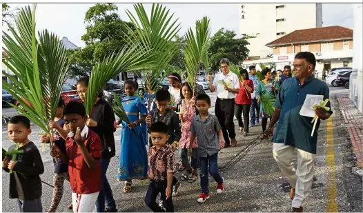  ??  ?? Faithful stroll: Parishione­rs singing hymns while waving palm leaves and palm crosses during the 400m-long procession around the church compound at St George’s Church Penang in Farquhar Street, George Town.