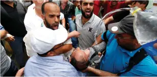  ?? (Mohammed Salem/REUTERS) ?? Palestinia­ns spray water on an UNRWA employee who tried to set himself on fire during a protest against job terminatio­n by UNRWA inside its headquarte­rs in Gaza City yesterday.