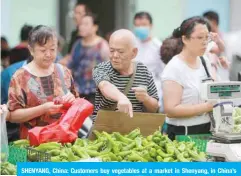  ??  ?? SHENYANG, China: Customers buy vegetables at a market in Shenyang, in China’s northeaste­rn Liaoning province yesterday. — AFP