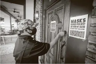  ?? Steve Gonzales / Staff photograph­er ?? Assistant manager Howard McElroy locks the entrance to Ron’s Bar in Houston on June 26 after Gov. Greg Abbott ordered the state’s bars to shut down a second time.