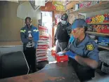 ??  ?? Police officers search a spaza shop in Diepsloot, confiscati­ng cigarettes and cigarette papers.