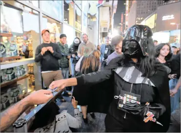  ?? PHOTO: BLOOMBERG ?? An employee wears a Darth Vader costume while handing out stickers to customers standing in line to enter the ‘Force Friday’ event for the release of new Star Wars: The Last Jedi products outside the Walt Disney store in New York. Star Wars helped US...