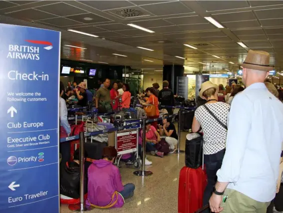  ?? (EPA) ?? Passengers stand at the British Airways check-in desk after an IT systems failure, In Rome, Italy