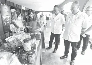  ?? — Gambar Bernama ?? TINJAU: Teo (dua kiri) diiringi Syirfan Indra (tiga kiri) melawat reruai produk makanan pada Majlis Pelancaran Program Cashless Society di Pusat Sebaran Maklumat Nasional (NaDi) Felda Taib Andak dekat Nilai semalam. Hadir sama Mohamad Rizal (empat kiri).