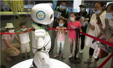  ?? — AP ?? Android assistance:
People looking at a robot on display at the trade fair in Beijing. China’s service robot market was estimated to be worth US$2.2bil (RM9.14bil) in 2019.