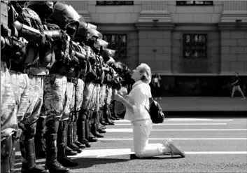  ?? AP Photo ?? A woman kneels in front of a riot police line as they block Belarusian opposition supporters rally in the center of Minsk, Belarus, on Sunday.