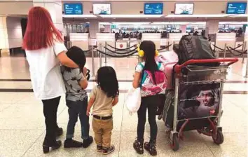  ??  ?? Anne and her three kids wait to board their flight to the Philippine­s at Dubai airport on Sunday. ■ The family was cheated by a PRO who disappeare­d with their passports and Dh24,000.