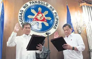  ??  ?? President Rodrigo Duterte administer­s the oath of office for new Environmen­t and Natural Resources Secretary Roy Cimatu, left, at the Malacanang presidenti­al palace in Manila on Monday.