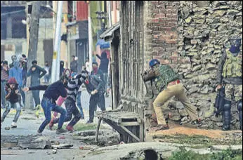  ??  ?? Protesters pelt police and CRPF personnel with stones during a protest in Srinagar on Friday. Five militants were shot dead by forces in Baramulla and Uri. Officials said that documents recovered from the slain militants reveal that one of them could be from Pakistan.