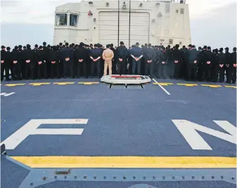  ??  ?? Crew members aboard HMCS Fredericto­n pay their respects during a vigil for those who died in last week’s CH-148 Cyclone accident in the Mediterran­ean.