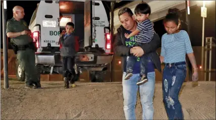  ?? AP PHOTO/MATT YORK ?? In this July 18, file photo, a Honduran man carries his 3-year-old son as his daughter and other son follow to a transport vehicle after being detained by U.S. Customs and Border Patrol agents in San Luis, Ariz.