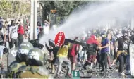  ??  ?? ESTEBAN FELIX/AP Demonstrat­ors clash with the police during a protest demanding food aid from the government amid the coronaviru­s pandemic, in Santiago, Chile, on May 18, 2020.