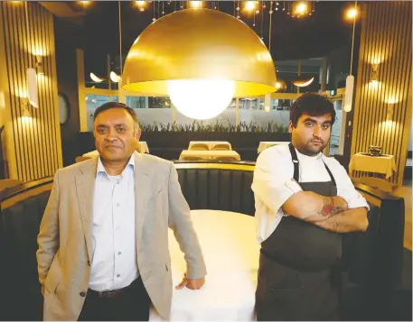  ?? TONY CALDWELL ?? Devinder Chaudhary, owner of Aiana, and his son chef and general manager Raghav Chaudhary, stand inside their empty restaurant on Friday. As much as it hurts, Devinder says he's resigned to closing his dining room again for the good of public health.