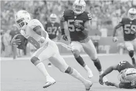  ?? JOE CAVARETTA/SUN SENTINEL ?? The Dolphins’ Jakeem Grant breaks free from Oakland Raiders defenders for his touchdown in the fourth quarter.