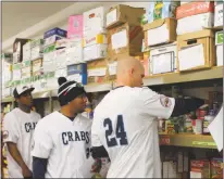  ?? STAFF PHOTO BY TIFFANY WATSON ?? Southern Maryland Blue Crabs players Carlos Gonzalez, Orlando Santos and Michael Snyder pack food boxes at the Charles County Children’s Aid Society in Waldorf last Thursday.