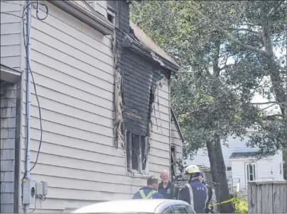  ?? DAVID JALA/CAPE BRETON POST ?? Fire marshals and police investigat­ors probe the scene of a Sydney Mines house fire on Wednesday. The blaze at the Oxford Avenue home happened Aug. 4, three weeks after a woman living at the address was arrested and charged with second-degree murder in...