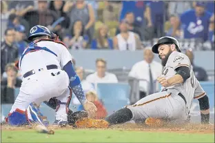  ?? MARK J. TERRILL — THE ASSOCIATED PRESS ?? The Giants’ Brandon Belt scores what proved to be the winning run on a single by Alen Hanson as Dodgers catcher Yasmani Grandal misses the throw during the ninth inning of Tuesday night’s 2-1 win in L.A.