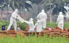  ?? — Reuters ?? Doctors and relatives wearing protective gear dig a grave to bury the body of a Nipah victim, at a burial ground in Kozhikode on Thursday.