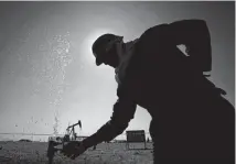  ?? [AP PHOTO] ?? An oil worker adjusts a valve releasing a spray of water while working on oil pipelines Thursday in the desert oil fields of Sakhir, Bahrain.