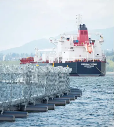  ?? JONATHAN HAYWARD / THE CANADIAN PRESS FILES ?? An oil tanker passes a floating chain link fence topped with razor wire at a marine terminal just outside of Vancouver. A group of senators is touring the west to determine the impact of oil tanker ban legislatio­n.