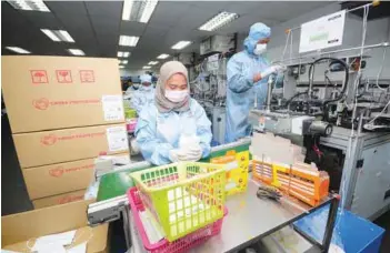  ?? – BERNAMAPIX ?? Workers packing face masks at the Cross Protection (M) Sdn Bhd factory in Meru, Klang yesterday. The plant has been instructed to boost production from 400,000 pieces to 500,000 a day to meet increased demand.