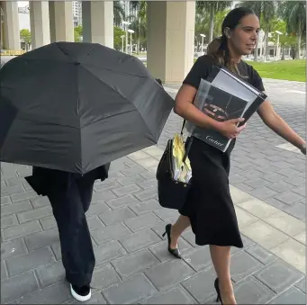  ?? JOSH GOODMAN — THE ASSOCIATED PRESS ?? Celebrity handbag designer Nancy Gonzalez hides under an umbrella as she walks with her lawyer Andrea Lopez outside the federal courthouse Monday in Miami.