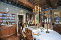 ??  ?? La salle à manger est éclairée par un lustre en cristal de Bohème restauré. Le vaisselier abrite un service de Gien aux initiales de l'arrière grand-père. Le trumeau de la cheminée est orné d'appliques dorées sur un fond bleu monarchiqu­e de la plus pure tradition.