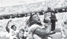  ?? WILLIAM WOTRING AP ?? West Virginia defensive lineman Dante Stills hoists the traditiona­l Black Diamond Trophy after the Mountainee­rs defeated Virginia Tech on Saturday afternoon.