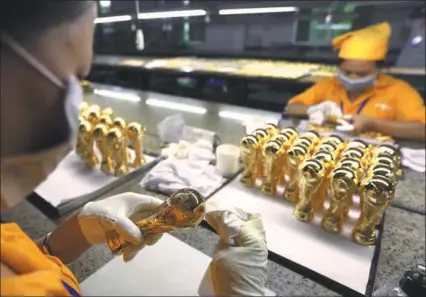  ?? QIU QUANLIN / CHINA DAILY ?? Replicas of the World Cup trophy are produced at Wagon Internatio­nal Co, an authorized manufactur­er of the World Cup-related products based in Dongguan, Guangdong province.