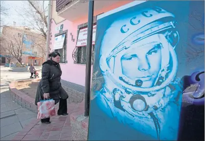  ?? ?? A woman walks past a poster of first cosmonaut Yuri Gagarin at the Russian leased Baikonur cosmodrome, Kazakhstan before the 50th anniversar­y of his flight on April 12, 1961