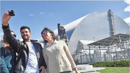  ?? SERGEI SUPINSKY/AFP/GETTY IMAGES ?? Tourists gather at Chernobyl’s New Safe Confinemen­t dome during a tour of the plant’s exclusion zone last year. The dome, which took nearly a decade to build, replaced a leaky steel and concrete structure.