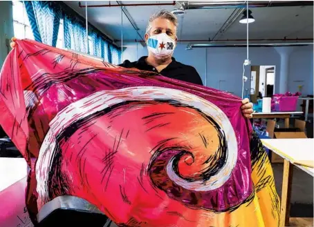  ?? JOSE M. OSORIO/CHICAGO TRIBUNE PHOTOS ?? Alan Spaeth, president of R&S Marching Arts, holds a marching band flag that was made at the Chicago factory.