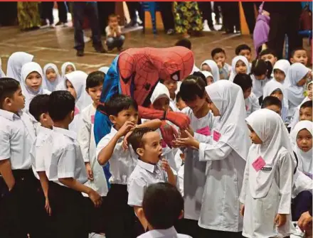  ?? PIC BY MOHD SYAFIQ RIDZUAN AMBAK ?? A man in a Spider-Man costume greeting pupils on their first day of school at SK Sultan Sulaiman 1 in Kuala Terengganu yesterday.