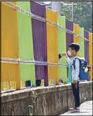  ??  ?? A student holds his mother’s hand through a fence as he arrives at the Ochi elementary school in South Korea yesterday. AP