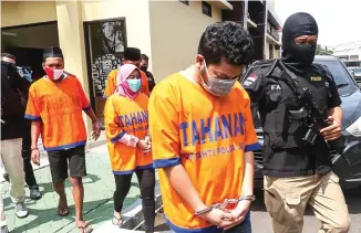  ??  ?? ANTARNEGAR­A: Foto kiri, tersangka digiring di Mapolda Jatim. Kepala Kantor Bea Cukai Tanjung Perak Aris Sudarminto (kiri) dan Kombespol Gatot Repli Handoko menunjukka­n sabu-sabu yang disita.