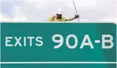  ??  ?? A worker secures a highway sign during installati­on over I-4 at Lee Road in Winter Park on March 8.