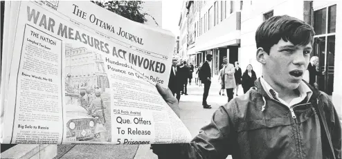  ?? Peter Bregg / the cana dian press files ?? A newsboy holds up a newspaper with a banner headline reporting the invoking of the War Measures Act in 1970.