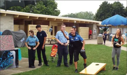  ?? TYLER RIGG — THE NEWS-HERALD ?? Patrolman Bruce Fedor (throwing) and members of the Panthers AllStar Cheerleadi­ng participat­e in a cornhole game as members of the Willoughby Law Enforcemen­t Exploring Post look on.