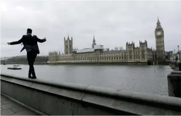  ??  ?? LONDON: A man balances as he walks along a wall above the River Thames backdroppe­d by the Houses of Parliament and Elizabeth Tower containing the bell knowh as “Big Ben”.