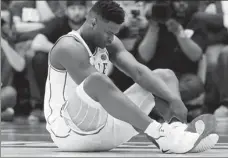  ?? AP ?? Duke’s Zion Williamson sits on the floor after sustaining an injury during an NCAA college game against North Carolina on Wednesday. As his Nike shoe blew out, Williamson sprained his right knee on the first possession of what became top-ranked Duke’s 88-72 loss to No 8 North Carolina.