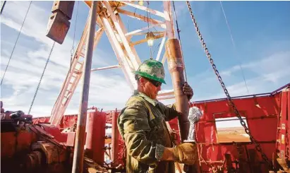  ?? James Durbin / Reporter-Telegram ?? Guy Cummings works to assemble a 90-foot section of pipe on the drilling floor of a rig this winter in Midland County. In February, oil companies recorded the biggest one-month infusion of stock market capital in history.