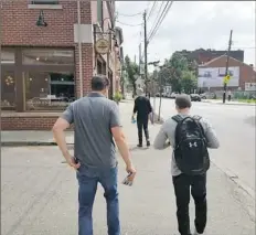  ?? Sara Bauknecht/Post-Gazette photos ?? Revtown co-founder and CEO Henry Stafford, center, leads the way as a group of employees walks along Butler Street in Lawrencevi­lle toward Round Corner Cantina as they continue their meetings.