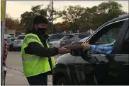  ?? RICHARD PAYERCHIN — THE MORNING JOURNAL ?? Lorain County Board of Elections staff member Andrew Irizarray gets the handoff of an absentee ballot from a voter Oct. 28 at the board’s drive-thru drop off station.