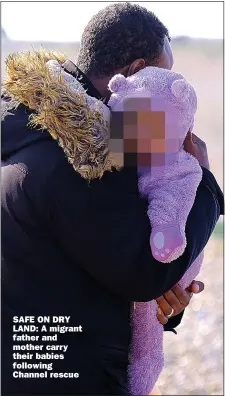  ??  ?? SAFE ON DRY LAND: A migrant father and mother carry their babies following Channel rescue