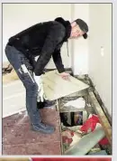 ??  ?? Bauarbeite­r Erik Bornschein (47) zeigt in der darüber liegenden Wohnung das Loch im Fußboden, durch das die Einbrecher in den Sex-Shop gelangten.