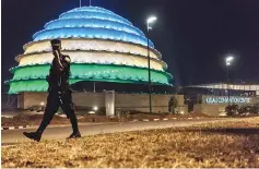  ??  ?? A Rwandan policeman walks past the dome of the Kigali Convention centre as it glows with the colours of the Rwandan flag in Kigali. The gleaming building is one of several developmen­ts that have shot up in the Rwandan capital, a window to an ambitious...