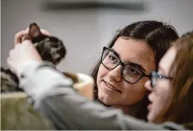  ?? ?? Reyna Smith, 13, right, and her sister Delainey, 15, pet a cat at Cat Haven Lounge. The sisters foster cats for Cuddle Buddies Rescue.