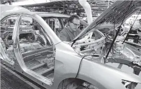  ?? ASSOCIATED PRESS FILE PHOTO ?? Production team member Darryl Ashley installs an inner dash silencer in a Camry on the assembly line at the Toyota Motor Manufactur­ing plant in Georgetown, Ky.