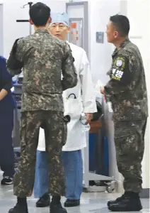  ??  ?? SOUTH KOREAN military officers, wearing armbands of the Joint Security Area of Panmunjom, talk with a doctor at a hospital in Suwon, south of Seoul, where the wounded North Korean defector was rushed for treatment, in this Nov. 13 photo.