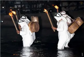  ?? ?? Ama carrying torches wade into the sea during the yearly ama festival